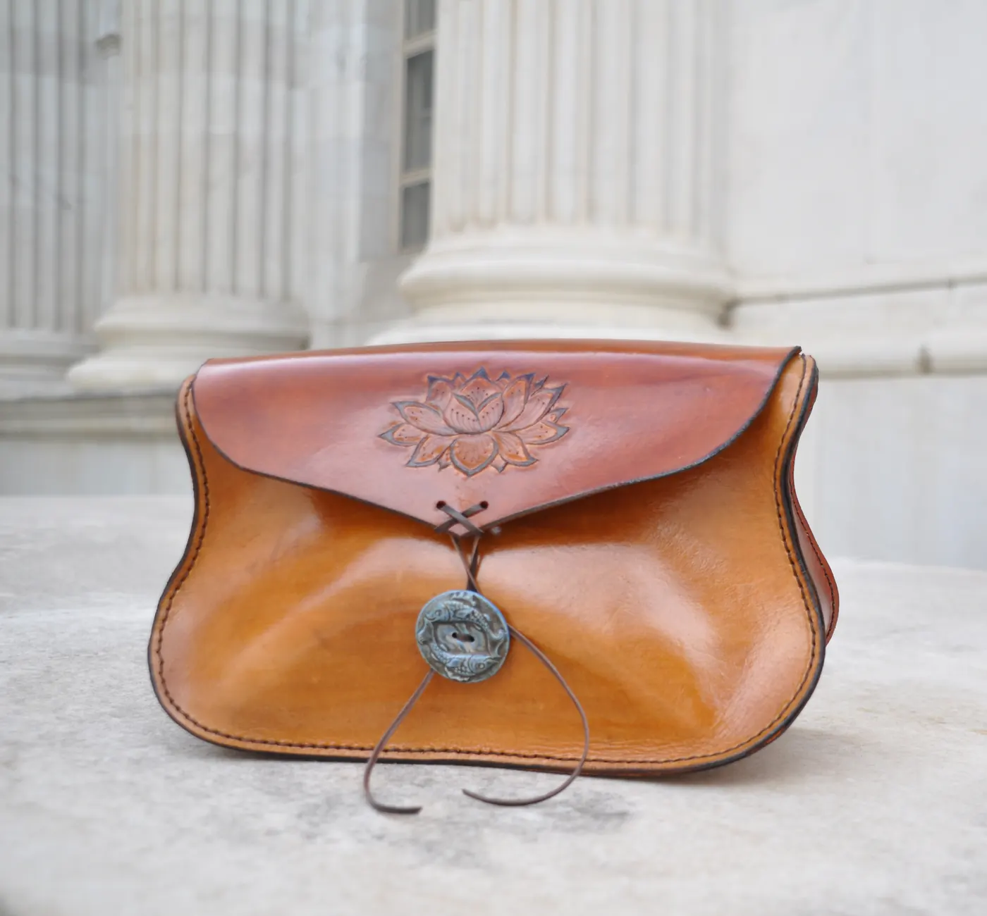 Tan leather clutch with a tooled lotus on the flap