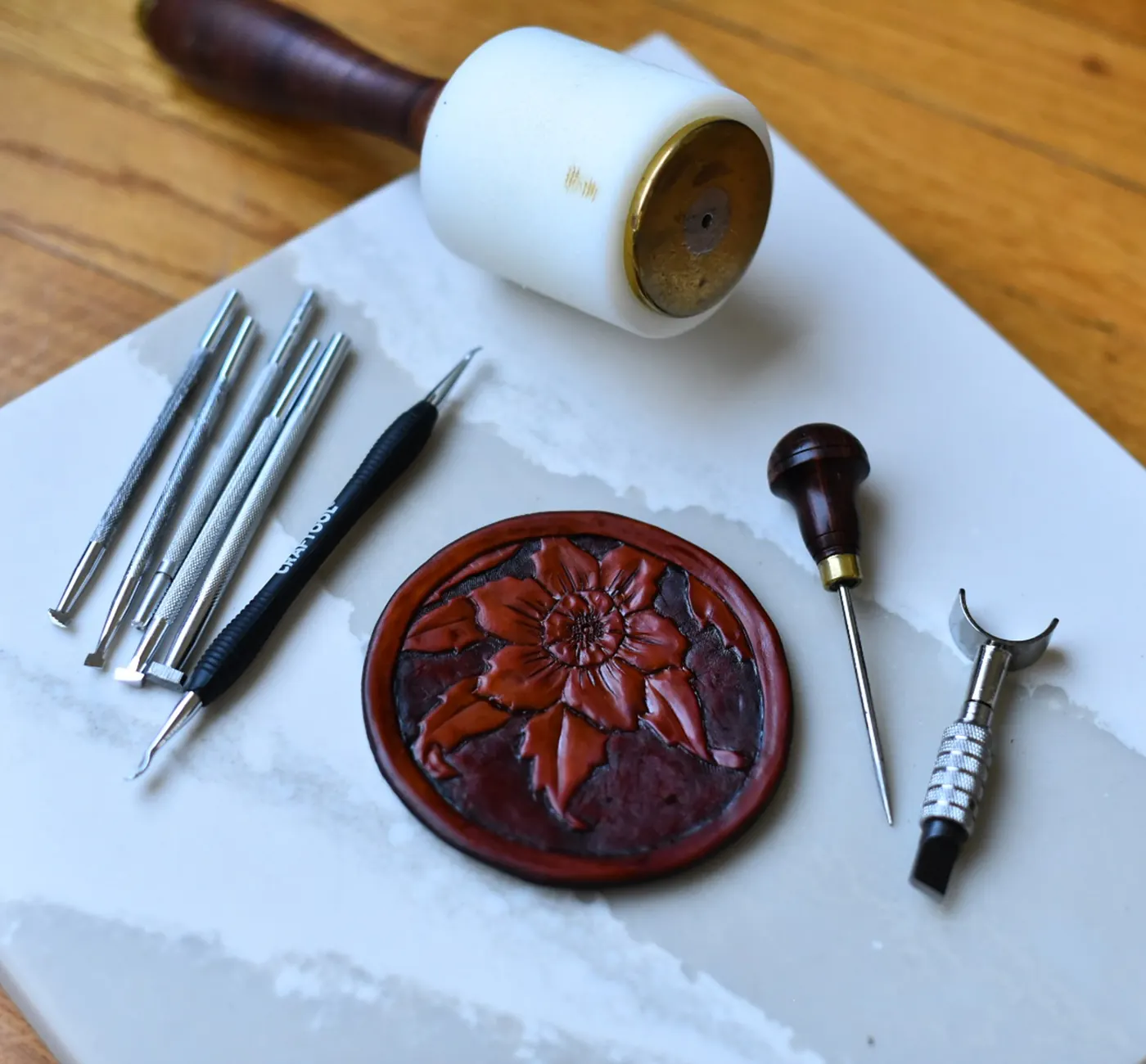 Leather tooling tools beside a hand-tooled flower medallion