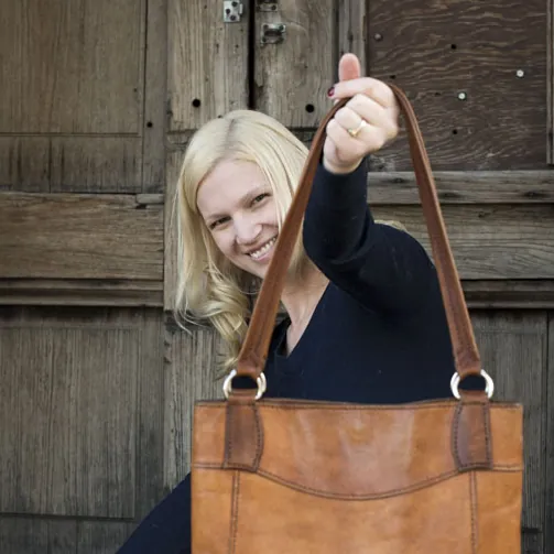 Jenna holding up a leather tote bag