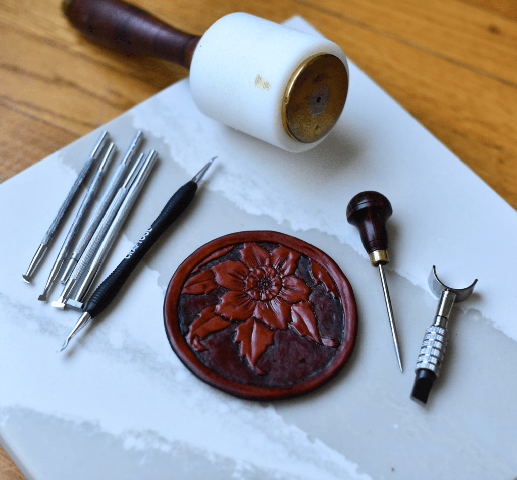 Leather tooling tools beside a hand-tooled flower medallion