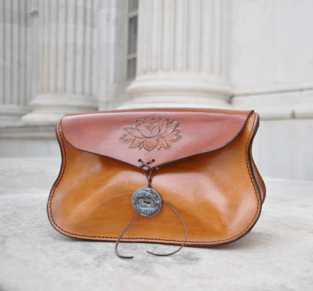 Tan leather clutch with a tooled lotus on the flap